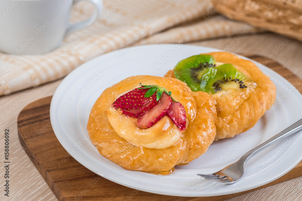 Danish pastry with fruit on plate and coffee cup