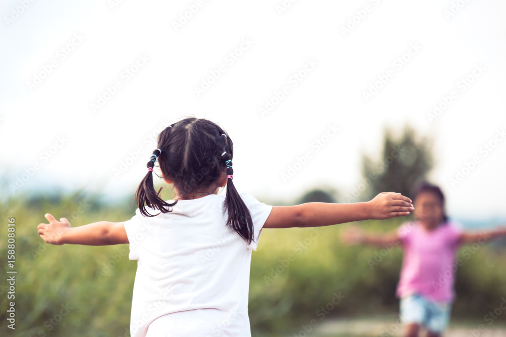 Back view of asian little girl raise her hand and waiting her sister to hug each other in vintage color tone Back view of asian little girl raise her hand and waiting her sister to hug each other in vintage color tone