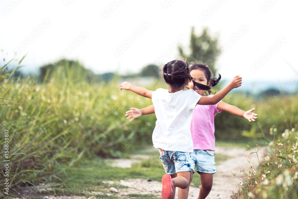 Two asian little girls running to give a hug each other in vintage color tone Two asian little girls running to give a hug each other in vintage color tone