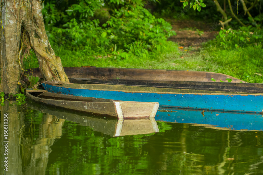 Old blue fishing wooden boat in a calm lake water Old blue fishing wooden boat in a calm lake water