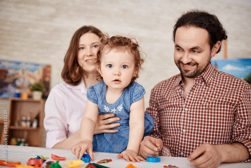 Happy family posing for portrait while playing with little daughter at home