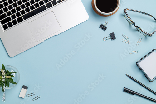 Top view workspace mockup on blue background with notebook, pen, coffee, clips and accessories. photo