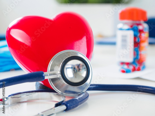 Red heart and stethoscope on doctor table photo