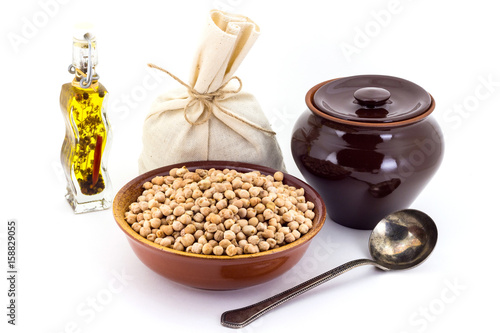 The composition of chick peas in a clay pial next to a clay pot and a copper spoon, photo