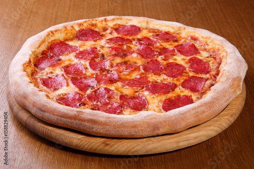 Italian pizza on the table, pepperoni, spices, tomatoes, cheese photo