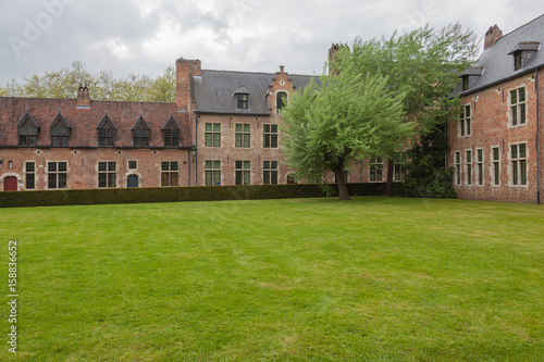 View of famous Grand Beguinage of Leuven with green lawn in foreground in spring cloudy day, Belgium