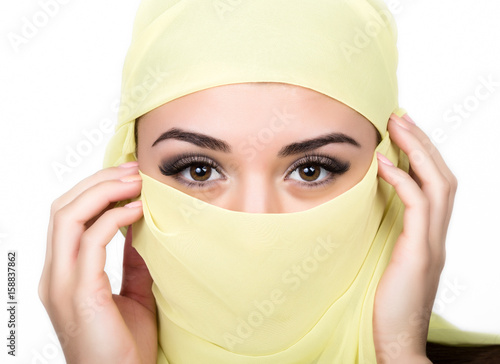 Closeup of beautiful young arabian woman in yellow hijab. Charm and beauty of the East. photo