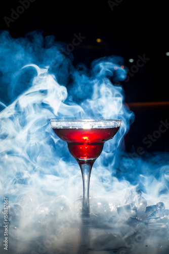 red cocktail with ice vapor, blue background