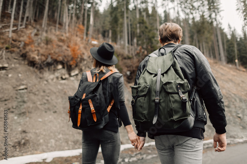 the couple are traveling. Boy and girl with backpacks travel. The couple walks along the path. Happy couple holding hands