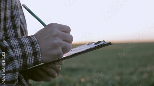 Farmer at dawn writes something in a notebook. Slow motion photo