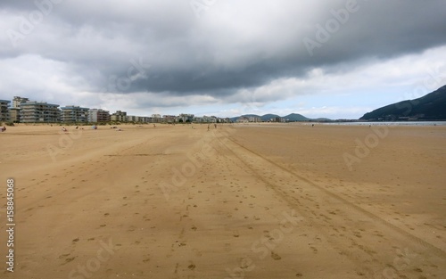 Sandy beach with footprints and houses in the background. Spain.