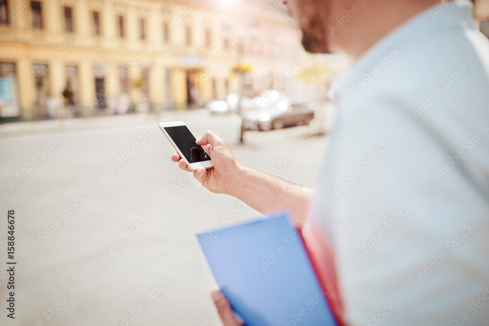 Close up photo of a young businessman with mobile phone and folder. Education, business, lifestyle concept Close up photo of a young businessman with mobile phone and folder. Education, business, lifestyle concept