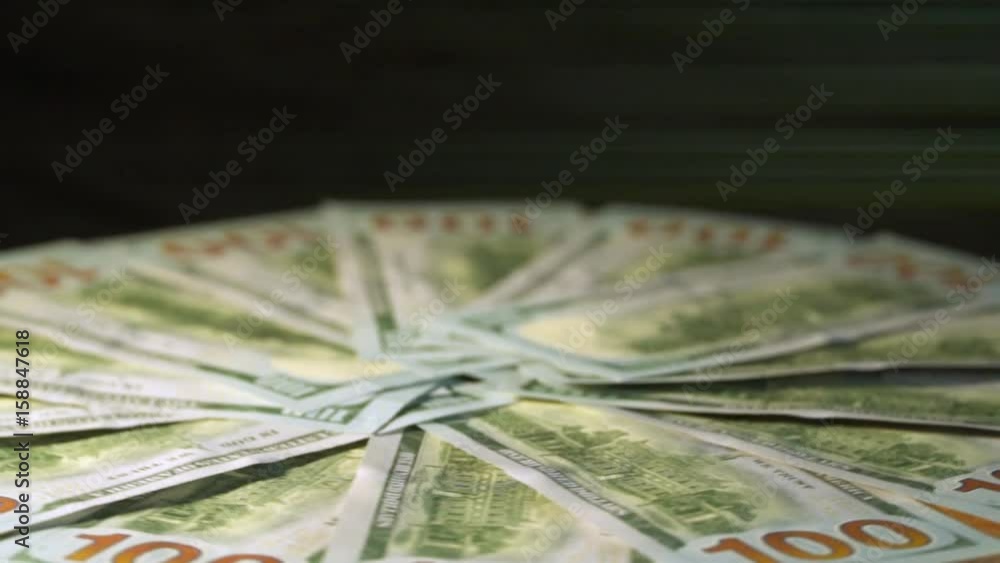 Dollars revolve against a black background. In the background light rays. US Dollars Dollars revolve against a black background. In the background light rays. US Dollars