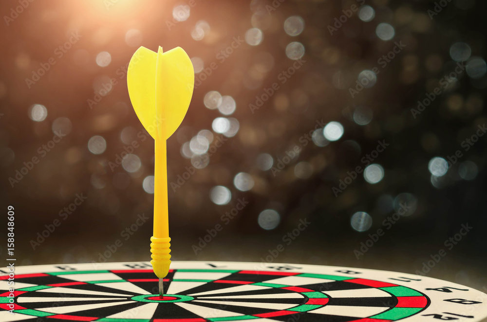 yellow arrow with over blurred background and target of dartboard or metaphor to target business concept yellow arrow with over blurred background and target of dartboard or metaphor to target business concept