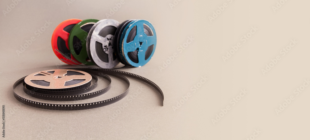 Vintage collection 8 mm cinema film reel. Retro design colorful celluloid  accessories for home video projector. Gray background, selective focus  Stock Photo