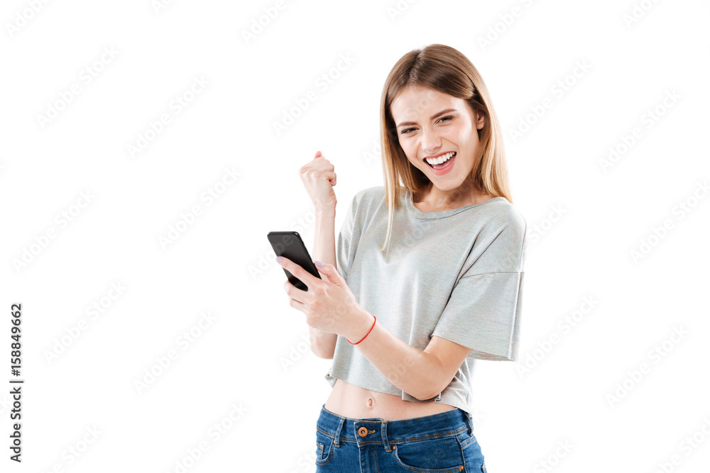 Happy joyful girl holding mobile phone and celebrating a win Happy joyful girl holding mobile phone and celebrating a win