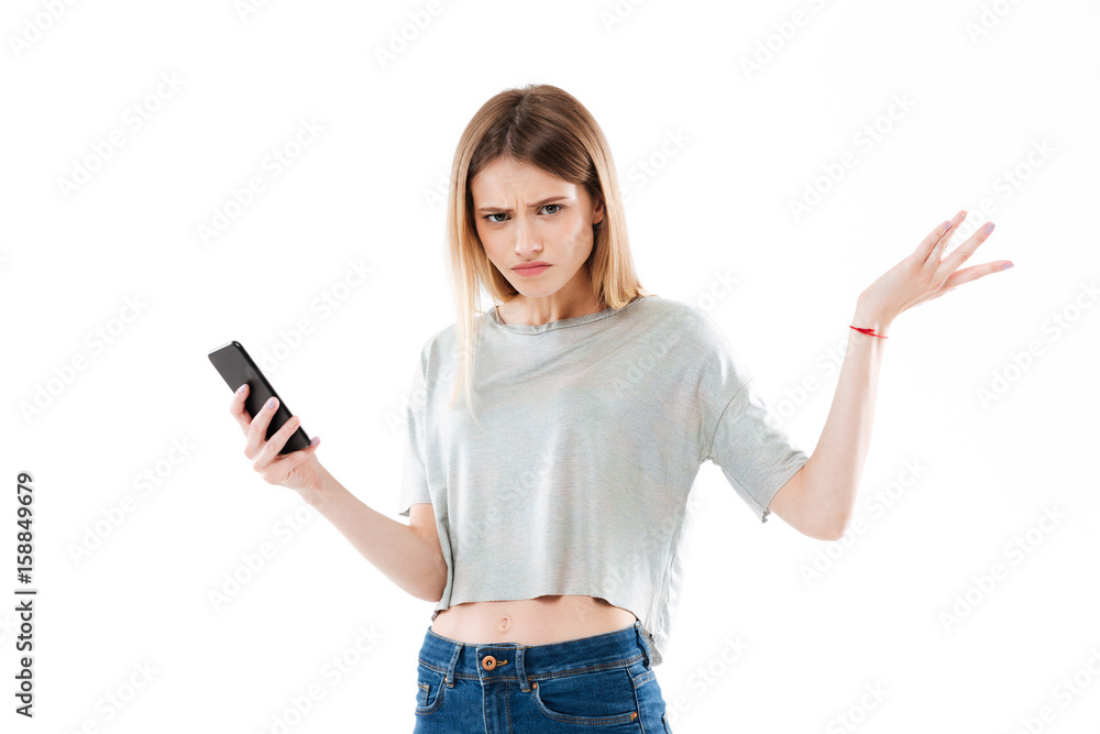 Young confused girl holding mobile phone and shrugging shoulders Young confused girl holding mobile phone and shrugging shoulders
