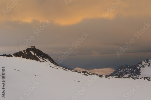 Alpine hut at stormy sunset