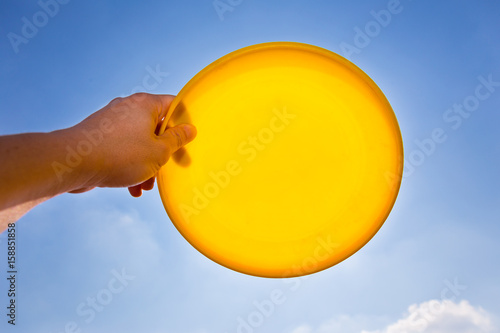 Foto male hand catching holding yellow frisbee disc against blue sky background