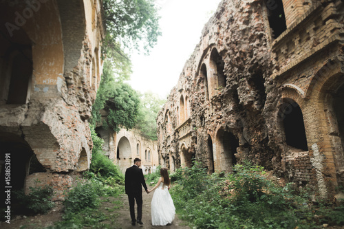 Just married poses and kissing with an old fortress on the background © olegparylyak