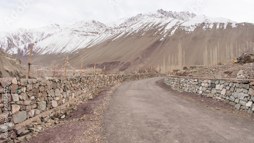 The walkway has stone wall and snow mountain background photo