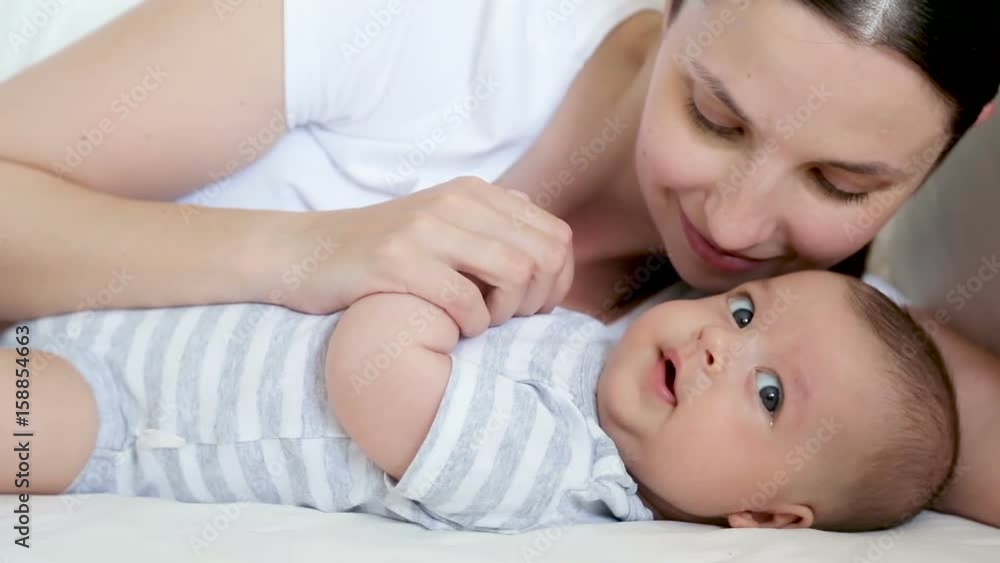 mom lies in bed with a newborn who yawns and trifling with him mom lies in bed with a newborn who yawns and trifling with him