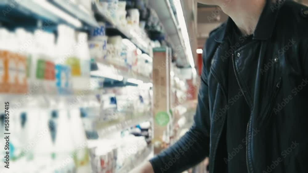 Young man picking a dairy in the supermarket Young man picking a dairy in the supermarket