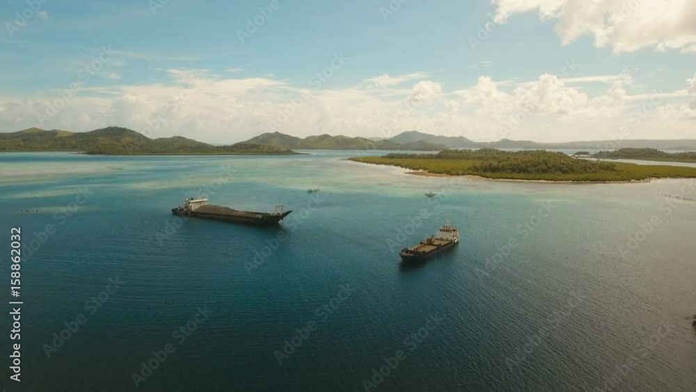 Aerial view Cargo and passenger ships in a beautiful lagoon on Siargao. Flying over the water surface of the sea with ships, blue sky and clouds. 4K video. Aerial footage. Philippines, Manila. Aerial view Cargo and passenger ships in a beautiful lagoon on Siargao. Flying over the water surface of the sea with ships, blue sky and clouds. 4K video. Aerial footage. Philippines, Manila.