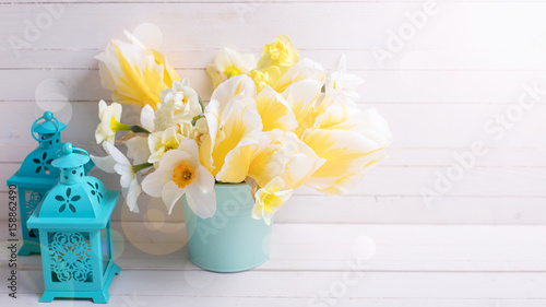 Fototapeta Naklejka Na Ścianę i Meble -  Bright yellow daffodils and tulips flowers and lanterns  on white wooden background.