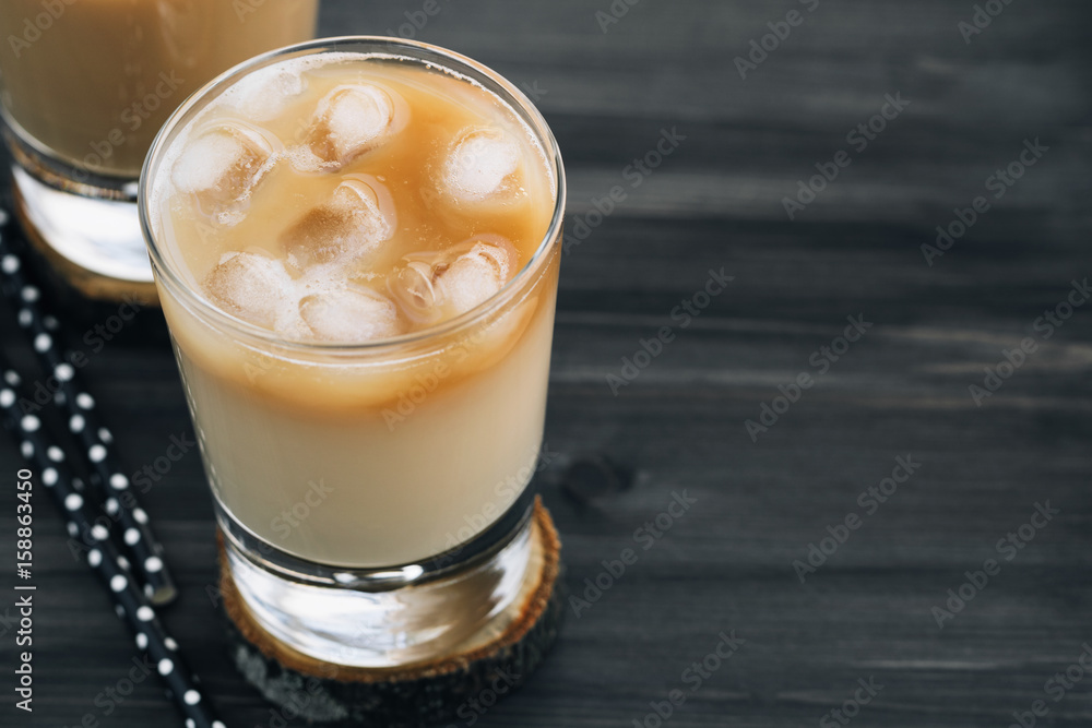 Close-up of a refreshing iced coffee with milk in glasses on a wooden black table. Close-up of a refreshing iced coffee with milk in glasses on a wooden black table.