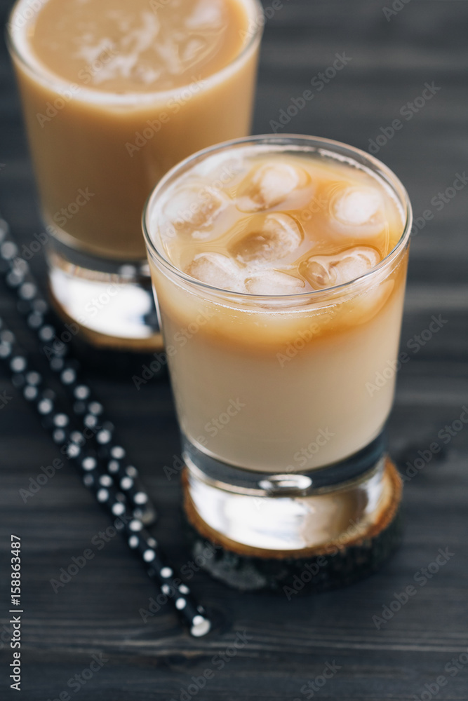 Close-up of a refreshing iced coffee with milk in glasses on a wooden black table. Close-up of a refreshing iced coffee with milk in glasses on a wooden black table.