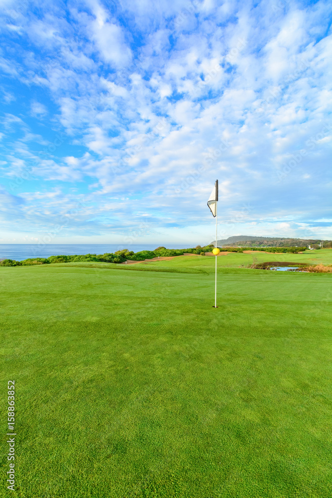 Obraz premium Golf pin on a beautiful seaside course with blue sky.
