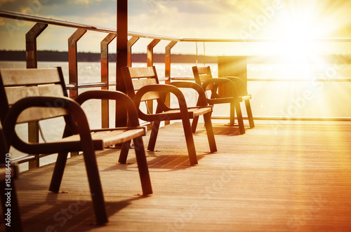 Amazing beach landscape with chairs for relaxation on wooden terrace. Bright sun rays. Travel background in vintage style.