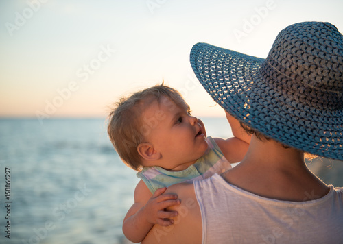 Mother with hat embracing little dougter at beach photo