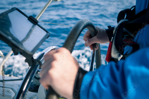 Hands of the skipper at the helm control of sailing boat