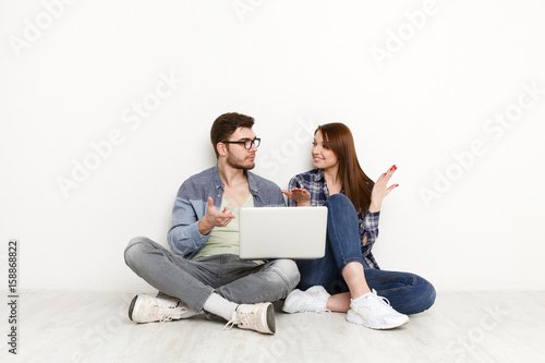 Couple shopping online, sitting on floor at home