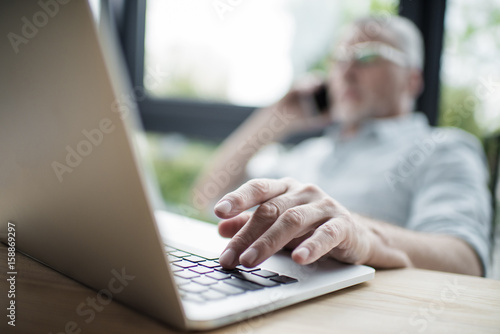 Close-up senior businessman working on laptop, selective focus