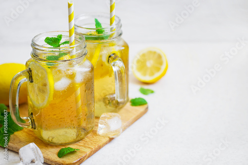 Green ice tea with lemon and mint in a glass jar.