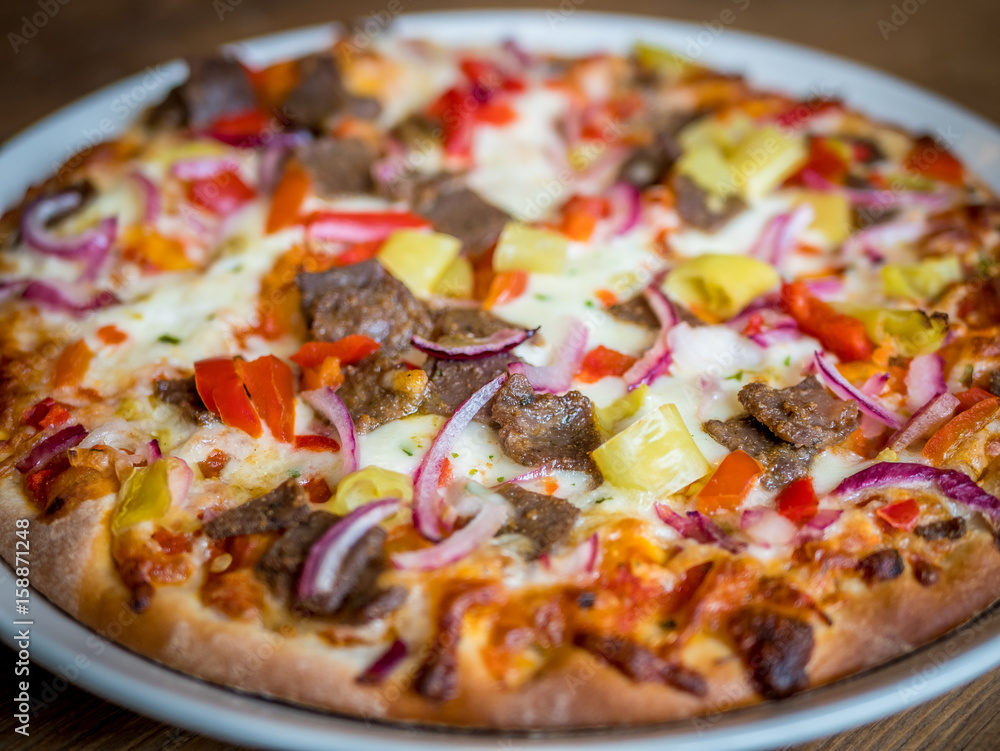 Close-up view fresh pizza served on plate on wooden table Close-up view fresh pizza served on plate on wooden table