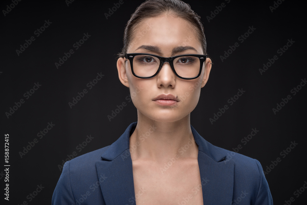 Portrait of young businesswoman in eyeglasses and formal wear looking at camera isolated on black Portrait of young businesswoman in eyeglasses and formal wear looking at camera isolated on black