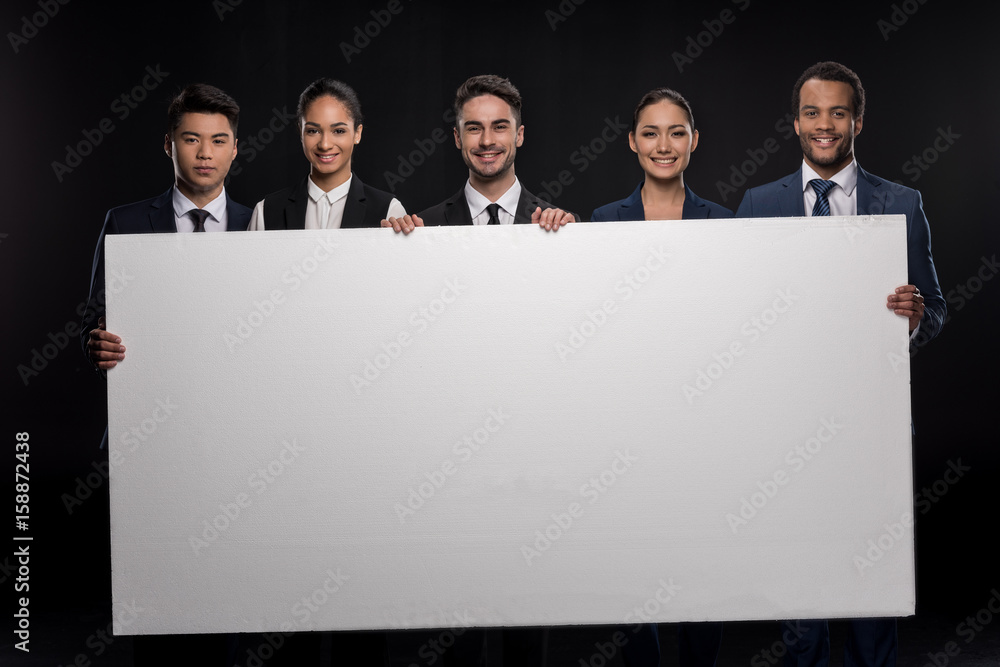 Group of happy business people holding blank billboard and looking at camera isolated on black Group of happy business people holding blank billboard and looking at camera isolated on black