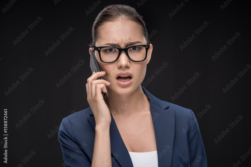 Portrait of young businesswoman talking on smartphone with smile isolated on black Portrait of young businesswoman talking on smartphone with smile isolated on black