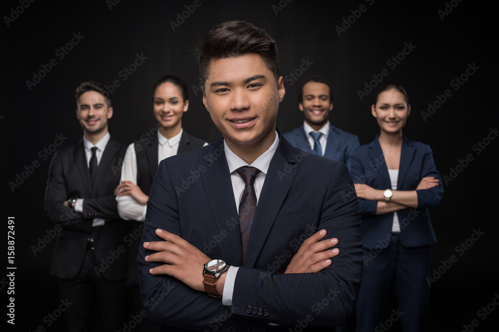 Group of smiling business people standing with arms crossed and looking at camera isolated on black Group of smiling business people standing with arms crossed and looking at camera isolated on black