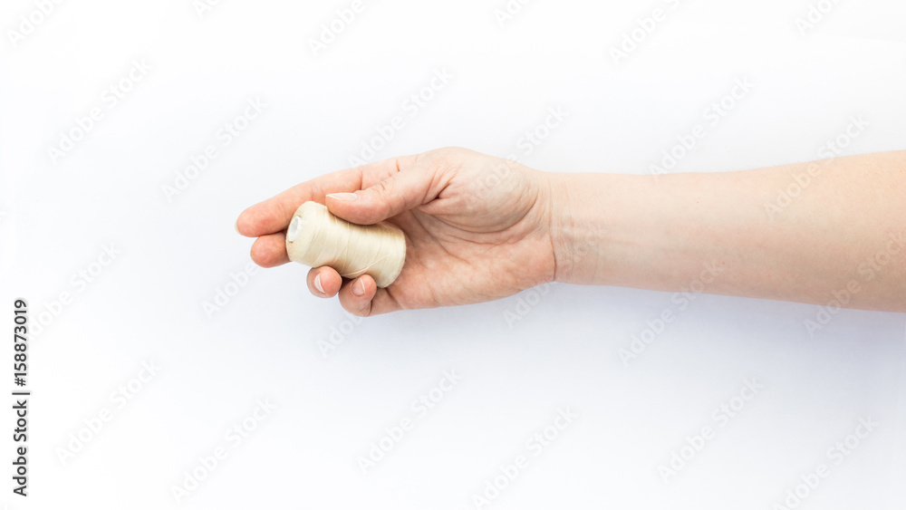 Female hand holding a spool of thread on white background. Female hand holding a spool of thread on white background.