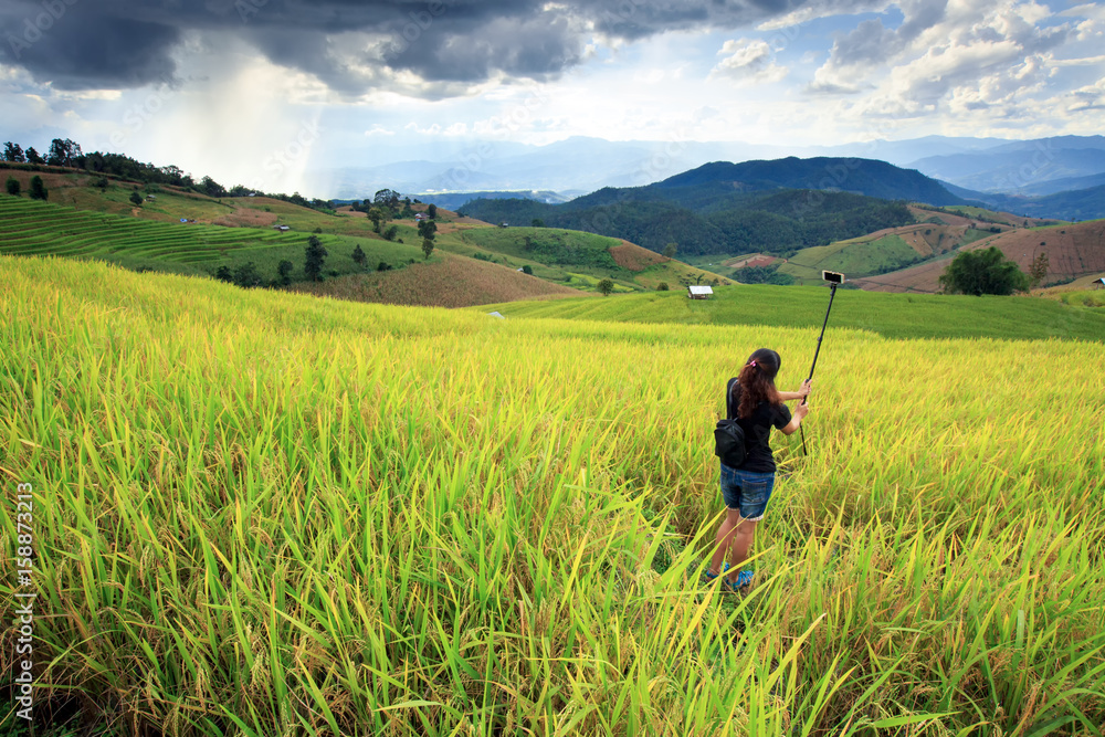 lady taking photo in rice field and mountain during storm coming