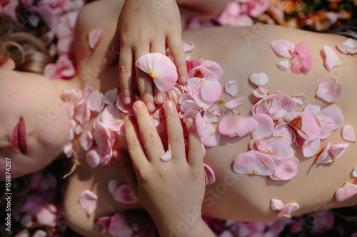 Person covered in flower petals, mid section, overhead view