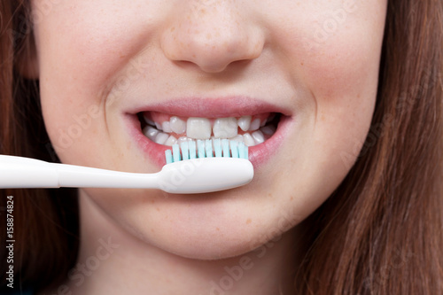 Cute smiling girl with permanent and milk teeth brushing her teeth. Dental hygiene.