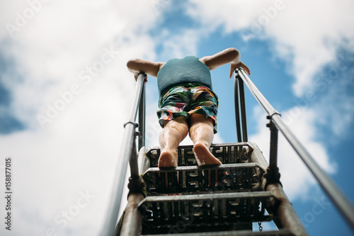 Young child standing on steps, low angle view, rear view
