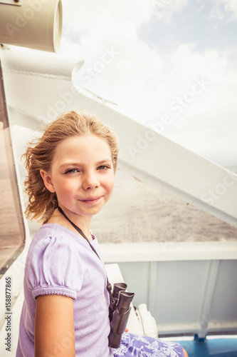Portrait of young girl on boat, smiling, binoculars round neck photo