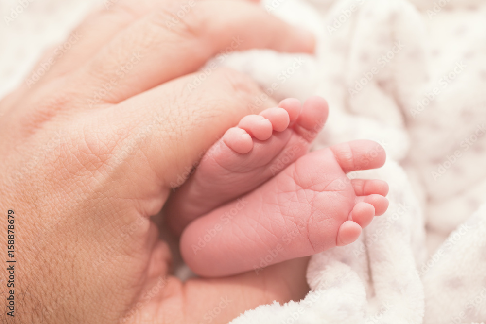 Feet of a newborn baby in the palm of his father Feet of a newborn baby in the palm of his father